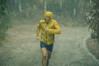 Athletic man jogging in extreme weather condition. Hail and rain