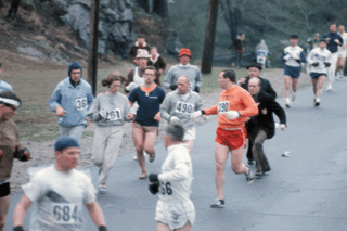 Boston-Marathon 1967: Renn­direktor Jock Semple (rechts, in der blauen Jacke) versucht Kath­rine Switzer (261) zu packen, ihr Freund Tom Miller (390) und Coach Arnie Briggs (490) geben ihr Geleitschutz.
