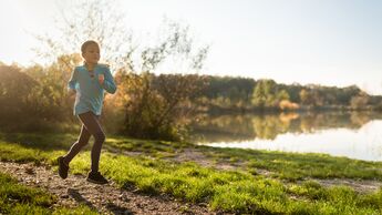 Ein Kind läuft auf einer schönen Strecke entlang eines Sees.