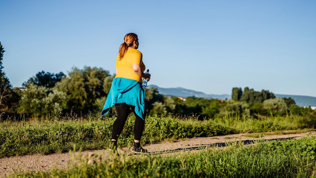Eine Frau läuft mit kleinen Schritten durch eine schöne Landschaft.