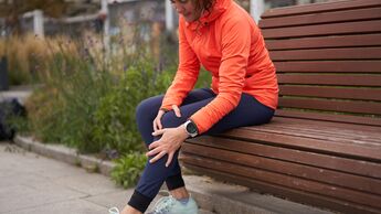 Eine Läuferin hält sich ihr schmerzendes Knie.