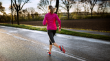 Frau beim Lauftraining auf regennasser Straße