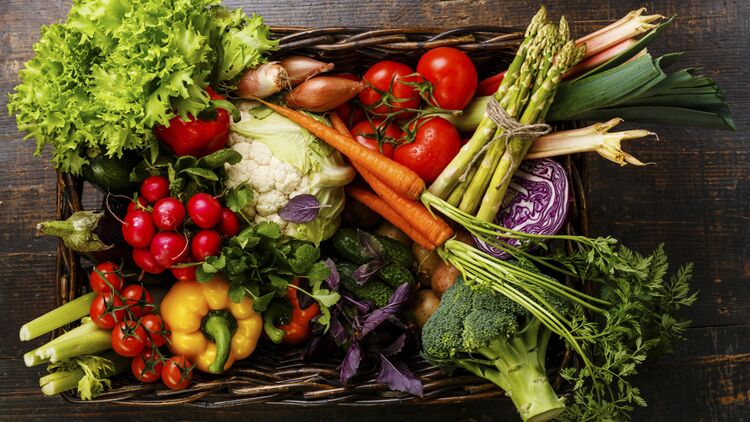 Fresh vegetables in basket on wooden background