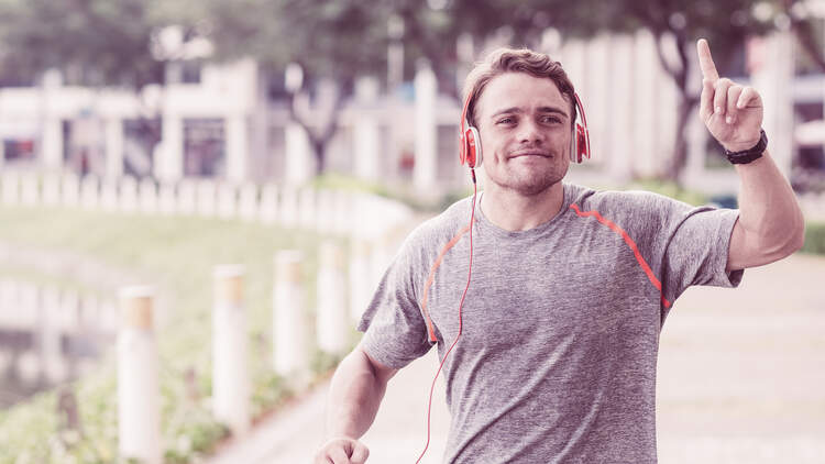 Happy Sportsman Running and Raising Finger in City