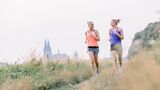 LISS-Training draußen: Zwei junge Frauen joggen in entspanntem Tempo.