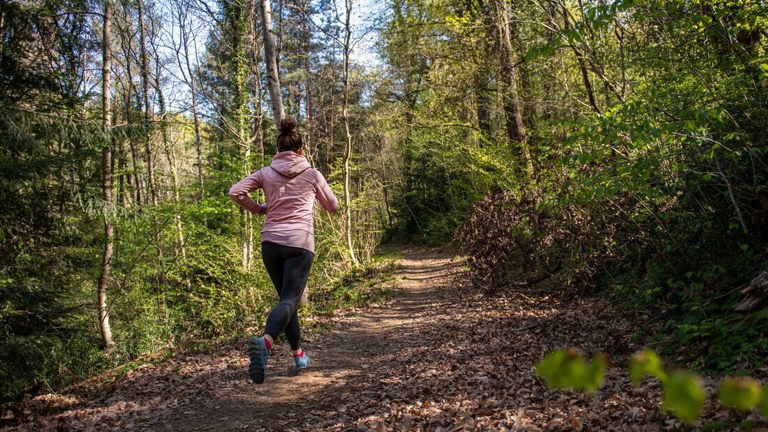 Läuferin im Frühling auf einem Waldweg