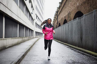 Langer Lauf in der Halbmarathon-Vorbereitung: Eine junge Frau läuft durch eine einsame Straße in der Stadt.