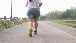 Laufen gegen Reiterhosen: Eine mollige junge Frau joggt auf einer Straße.