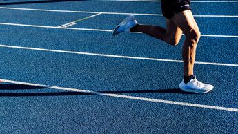 Lauftraining auf einer Laufbahn, Seitenansicht der Beine eines Läufers.