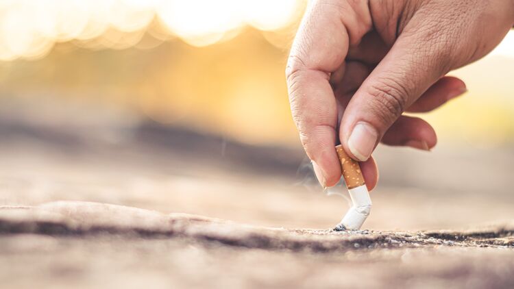 Rauchen aufhören: Jemand drückt eine Zigarette auf dem Boden aus.