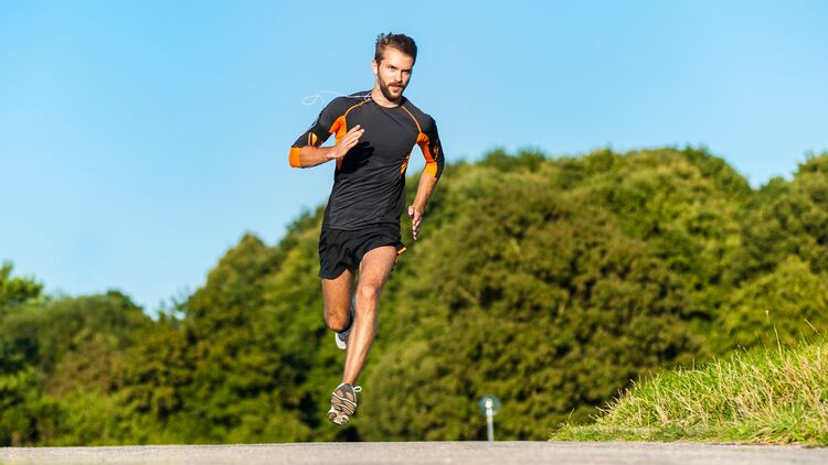 Trainingsplan 10 Kilometer unter 45 Minuten; junger Mann beim zügigen Lauftraining auf einer Straße