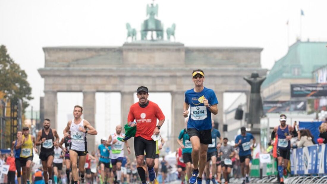 Vor dem Brandenburger Tor laufen Läufer angestrengt beim Marathon